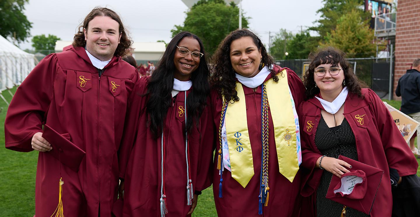 Four students smiling at graduation